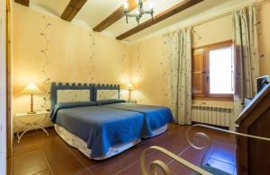 sypialnia z niebieskim łóżkiem i oknem w obiekcie Casa Rural La Yedra w mieście Galve