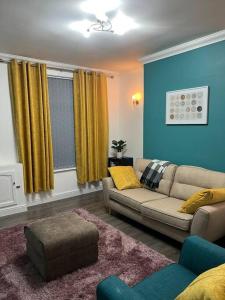 sala de estar con sofá y cortinas amarillas en Comfortably furnished 2 bedroom home in Bolton en Bolton