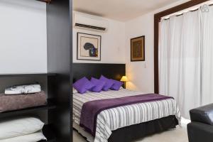 1 dormitorio con 1 cama grande con almohadas moradas en Apartments StudioCopa, en Río de Janeiro