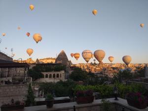 a group of hot air balloons flying over a city at Guzide Cave Hotel in Goreme