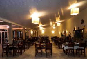 Un comedor con mesas, sillas y luces. en Molise Hotel Fazenda, en Serra Negra