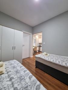 a white bedroom with two beds and a desk at Medjugorje Apartments Centre in Međugorje
