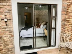Habitación con puerta de cristal y cama. en URRR Casa on Msasa, en Randburg