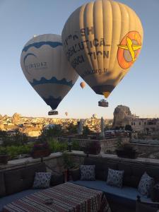 two hot air balloons flying over a city at Guzide Cave Hotel in Göreme
