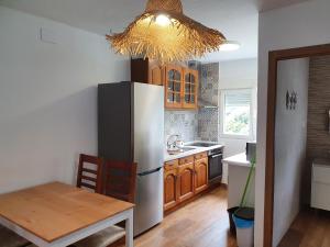 uma cozinha com um frigorífico, uma mesa e um lustre em vivienda vacacional casa tames em Ribadesella