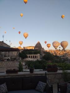 um grupo de balões de ar quente sobrevoando uma cidade em Guzide Cave Hotel em Goreme