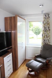 a living room with a chair and a television at Boardinghouse My Maison in Morschen