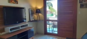 a living room with a television and a door to a patio at Praia Boulevard Flat Porto Bahia in Porto Seguro