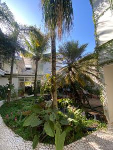a garden with palm trees and flowers in front of a building at Hotel e pousada oca in Holambra