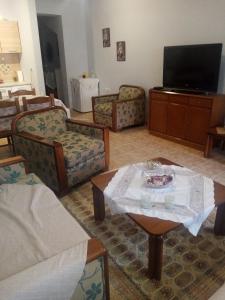 Haras'house في Asvestokhórion: غرفة معيشة مع كراسي وطاولة وتلفزيون
