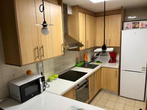 kuchnia z drewnianymi szafkami i białą lodówką w obiekcie Residencia Vista Alegre w Santiago de Compostela