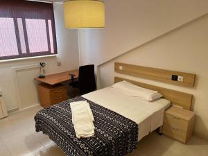 sypialnia z łóżkiem, biurkiem i oknem w obiekcie Residencia Vista Alegre w Santiago de Compostela