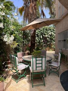 een patio met een tafel en stoelen en een parasol bij Magnifique villa avec un grand jardin et une cascade in Agadir