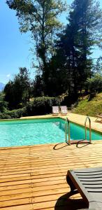 una gran piscina con una terraza de madera y sillas en Villaggio Barilari, en Minucciano