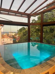 uma grande piscina numa casa com janelas em Cobertura Duplex com piscina e Suítes Barão Vermelho em Morro de São Paulo