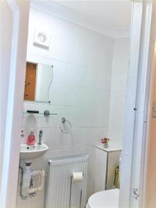 a white bathroom with a toilet and a sink at Devonshire house-3.3ml from Wimbledon centre court in London