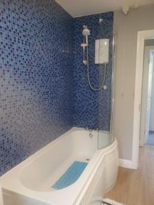 W wyłożonej niebieskimi kafelkami łazience znajduje się wanna i prysznic. w obiekcie Green Street Retreat w mieście York
