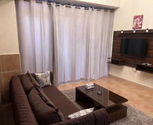 a living room with a brown couch and a television at Magic Studio Pool View, New Cairo in Cairo