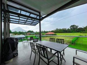 a patio with tables and chairs and a view of a field at Brisas del Volcán BnB in Fortuna