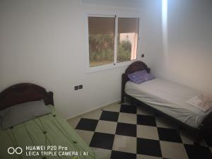 a small bedroom with a bed and a checkered floor at Daya Rentals in Asilah