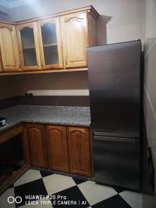 a kitchen with wooden cabinets and a black refrigerator at Daya Rentals in Asilah