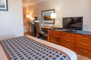 a hotel room with a bed and a desk with a television at Riviera Inn in Port Angeles