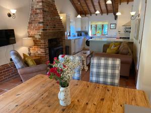 - un salon avec une table et des fleurs dans l'établissement Brundish Suffolk Barn 2 Bed Idyllic 6 acres, à Wilby