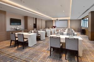 Holiday Inn & Suites Sanya Yalong Bay, an IHG Hotel في سانيا: قاعة اجتماعات مع طاولات وكراسي وشاشة