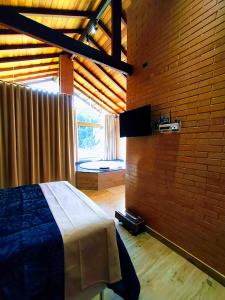 a bedroom with a bed and a large window at Chalés Estância Campestre in Capitólio