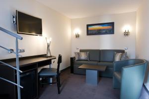 a hotel room with a couch and a desk at Hotel Choiseul Opera in Paris