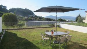 a table and chairs with an umbrella in the grass at AL CASA DE SÃO ROQUE in Caminha
