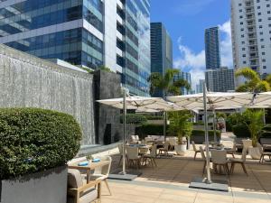 eine Terrasse mit Tischen, Stühlen und Sonnenschirmen in der Unterkunft Four Seasons Hotel Miami - Luxury Private Residences in Miami
