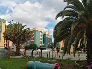 a playground in a park with palm trees and buildings at Hermoso Apartamento al Norte cerca de la Embajada Americana in Quito