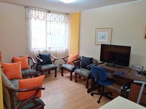 a living room with chairs and a desk with a television at Hermoso Apartamento al Norte cerca de la Embajada Americana in Quito