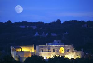 a night view of a castle with the moon in the background at Masseria Cervarolo in Ostuni