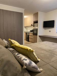 a room with a bed with pillows and a kitchen at Increíble Departamento Studio - Centro Antofagasta in Antofagasta