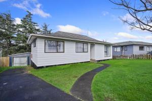 a white house with a grass yard in front of it at Family 3BR Home with Netflix and Fully Fenced Yard in Auckland