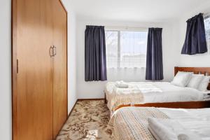 um quarto com 2 camas e uma janela em Family 3BR Home with Netflix and Fully Fenced Yard em Auckland