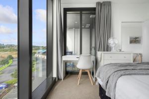 a bedroom with a bed and a desk and a window at Cool Ra-mada Hideaway with air-con and deck in Auckland
