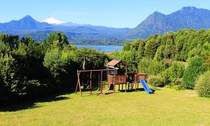 a playground in a field with mountains in the background at Cabañas Ruka Rayun vista y acceso al lago en Coñaripe in Panguipulli