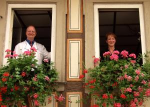 Ein Mann und eine Frau, die mit Blumen aus dem Fenster schauen in der Unterkunft AKZENT Hotel Am Bach in Dettelbach