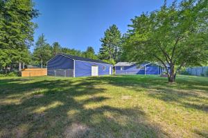 un gran patio con un edificio azul y un árbol en Prudenville Retreat with Yard about 1 Mi to Lake!, en Houghton Lake