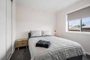 Habitación blanca con cama y ventana en Smiggins Stays - Spacious and Stylish, en Thurgoona