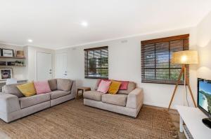 a living room with two couches and a tv at Lyons Cottage - a quaint Whalers Cottage in heart of Port Fairy in Port Fairy