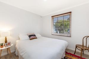 a white bedroom with a bed and a window at Lyons Cottage - a quaint Whalers Cottage in heart of Port Fairy in Port Fairy
