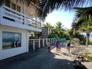 un grupo de personas caminando por la playa cerca de un edificio en RedDoorz @ Isla Virginia Beach Resort Aurora Baler, en Baler