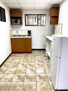 uma cozinha com um frigorífico branco e piso em azulejo em Hermoso apartamento en la capital de Costa Rica em San José