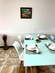 una mesa de comedor azul con platos y sillas blancos en Hermoso apartamento en la capital de Costa Rica, en San José