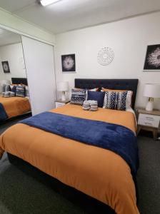 Schlafzimmer mit einem großen Bett mit blauer und orangefarbener Bettwäsche in der Unterkunft Nomads Rest in Gympie