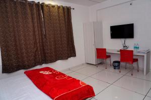 um quarto com uma secretária e uma mesa com cadeiras vermelhas em Heaven Accommodations em Rajkot